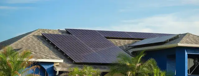 Solar panels on a pale gray tiled roof under a blue sky