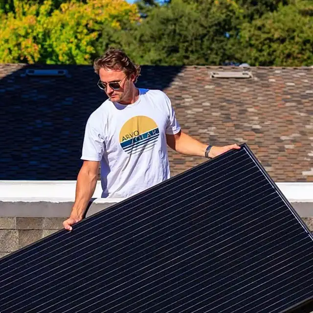 Arvo employee in an Arvo Solar shirt holding a solar panel